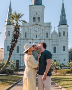 parents kissing baby in front of Jackson Square in New Orleans